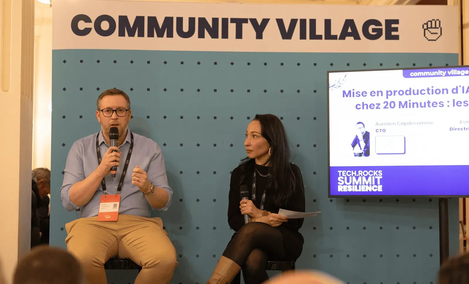 Session « Mise en production d’IA chez 20 Minutes » au Community Village : un intervenant et une modératrice assis, micro en main
