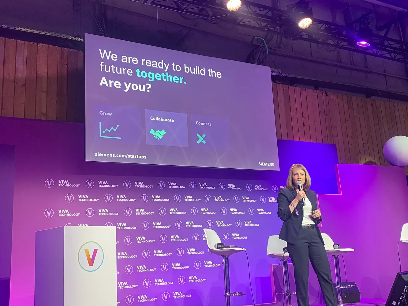 VivaTech 2024, Exec Arena : une intervenante au micro devant l’écran Siemens « We are ready to build the future together. Are you? »